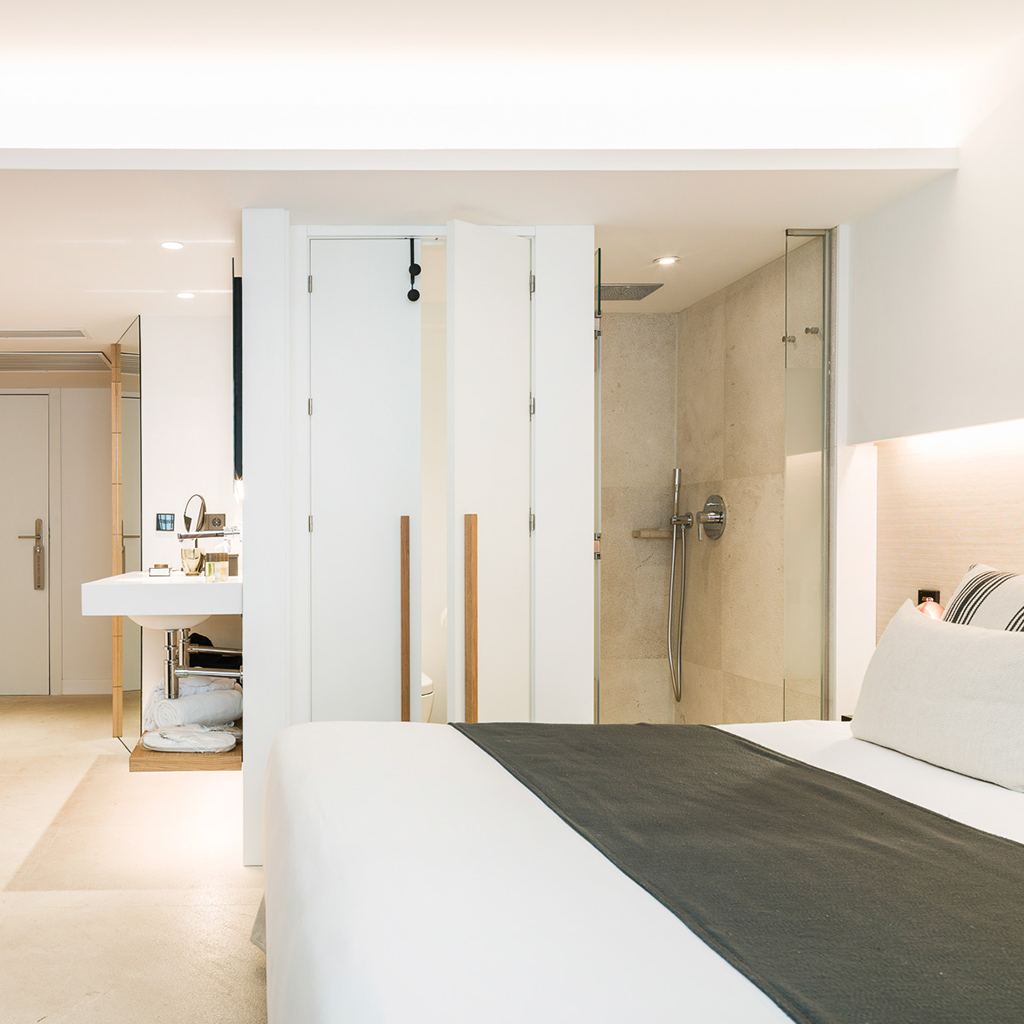 Guest room with an open ensuite bathroom, walk-in shower and freestanding sink visible from the bed