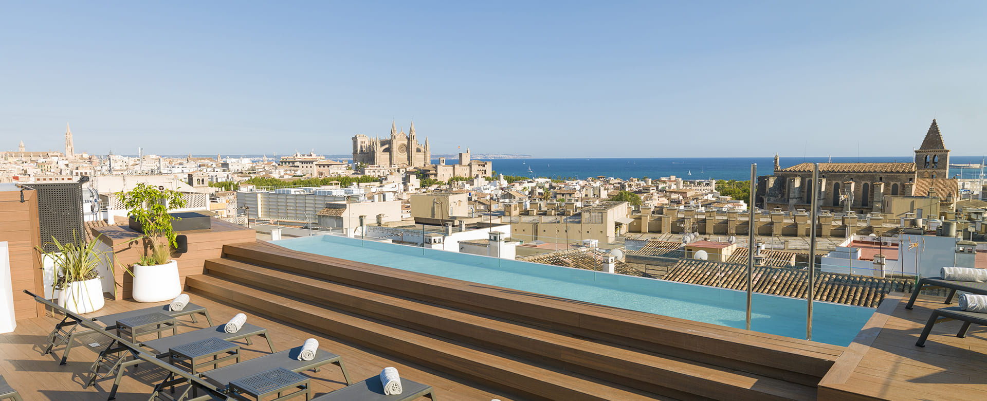 Rooftop infinity pool and sun loungers with a view over Palma's rooftops to the Cathedral and the bay