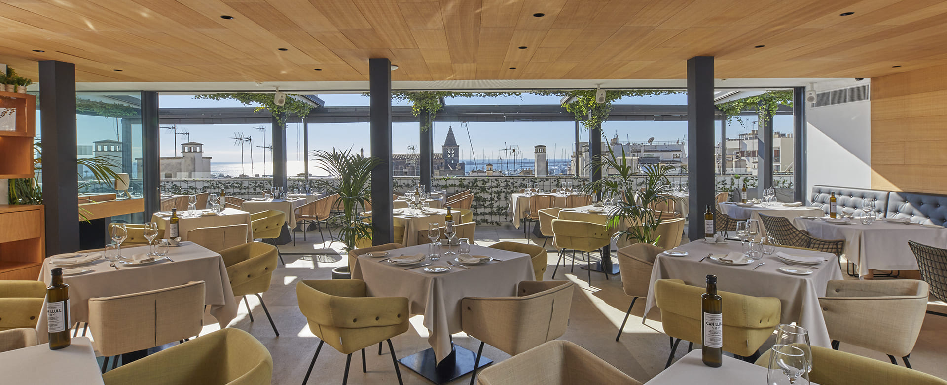 CUIT restaurant's covered rooftop terrace, set tables with olive oil bottles and wine glasses, looking out over the city and harbour