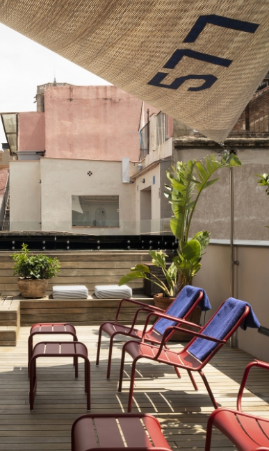 Hotel Neri rooftop terrace with red lounge chairs and plants