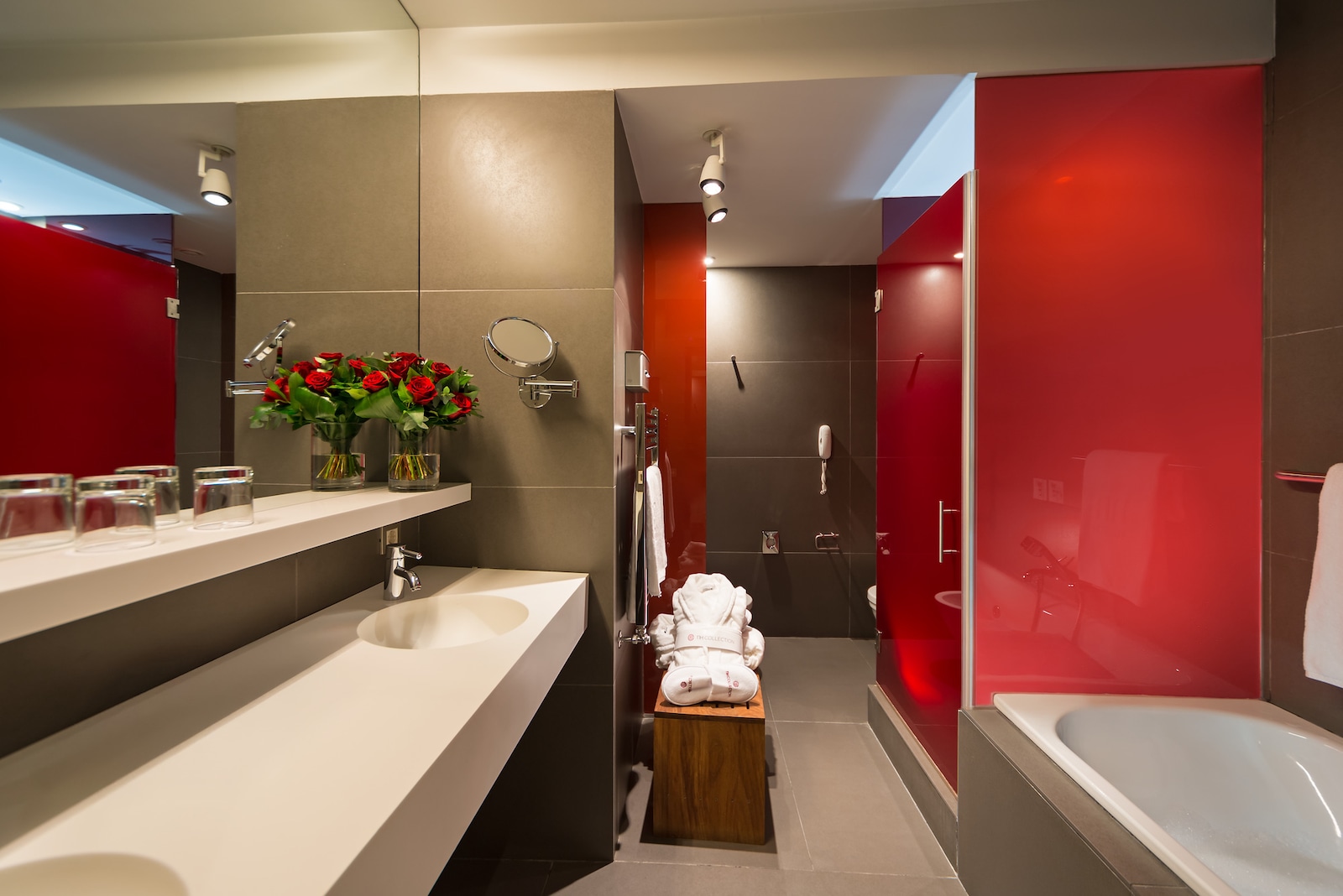 Suite bathroom with a red glass shower partition and a bathtub