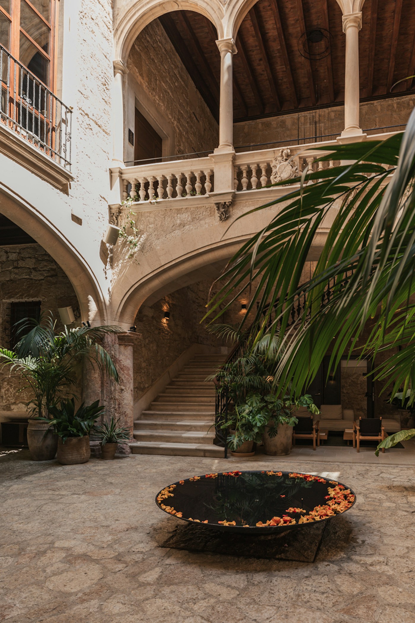 Historic stone courtyard lobby with an arched staircase and palm plants