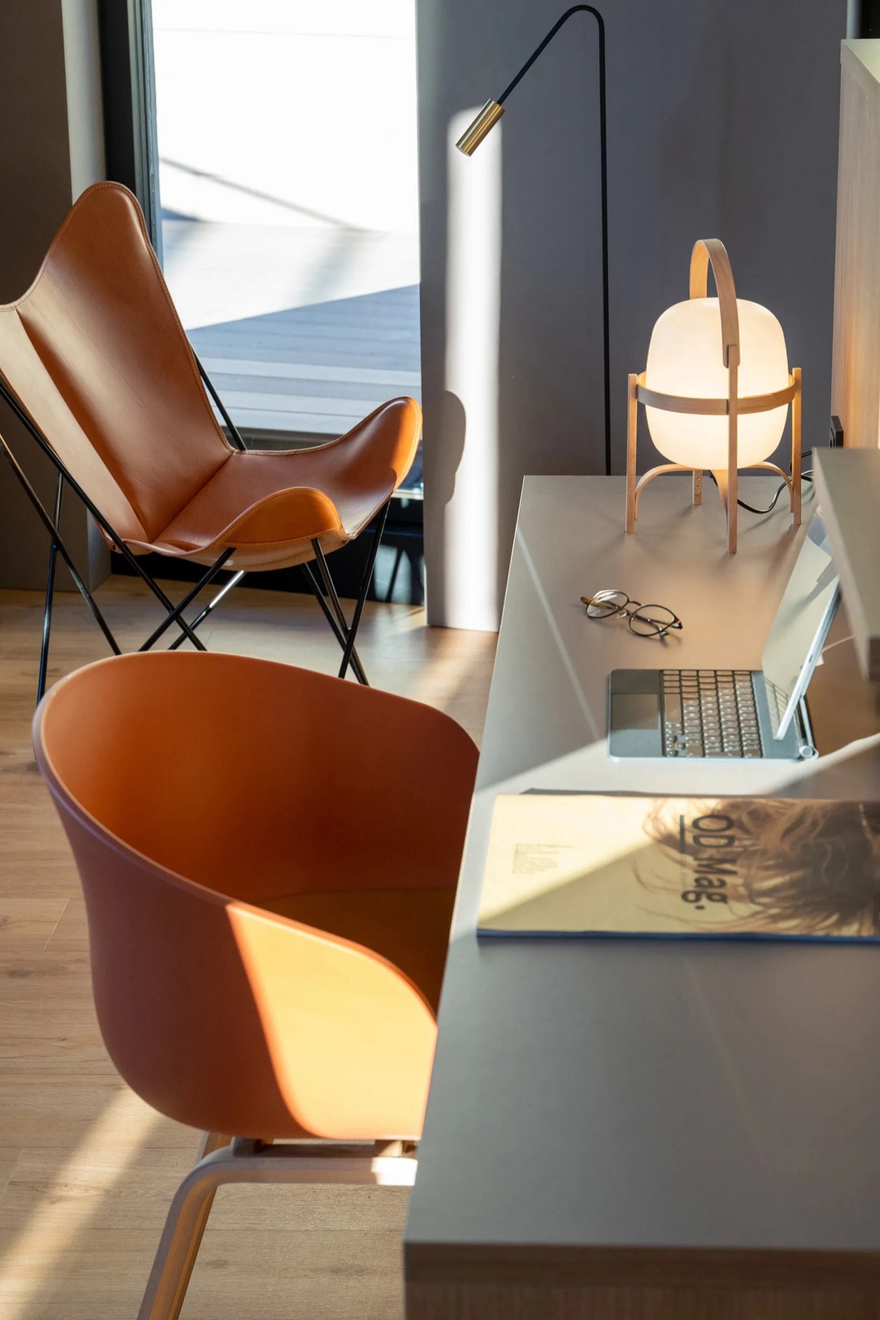 A co-working corner off the lobby with two leather armchairs, a desk with a laptop and glasses, and a lit table lamp.