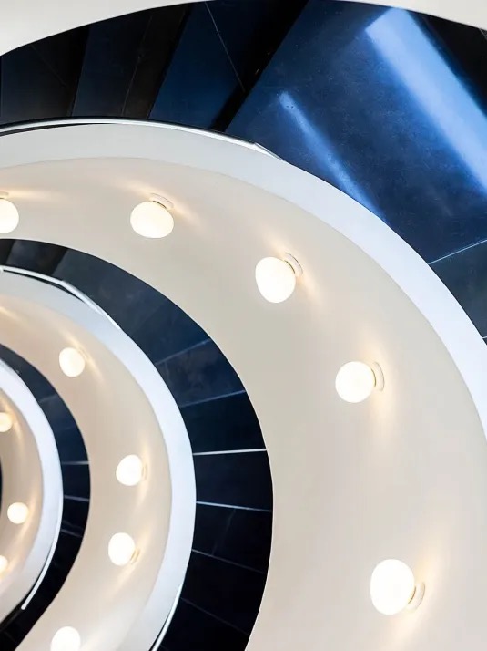 Spiral staircase viewed from below with round pendant lights along the curve