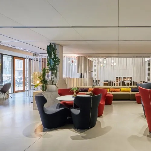 Ohla Eixample lobby lounge with red and black armchairs and greenery