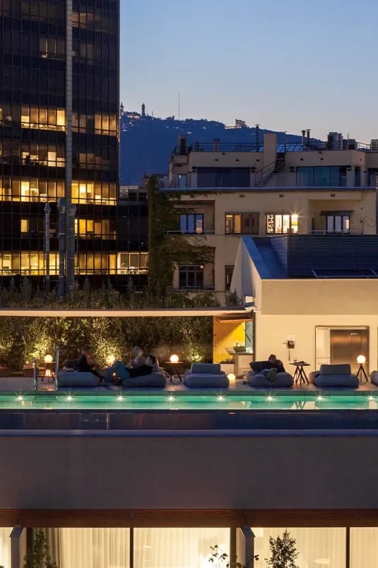 Ohla Eixample rooftop pool terrace at dusk with the Barcelona skyline