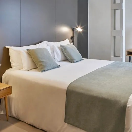 Ohla Eixample guest room with a grey headboard and a green throw blanket