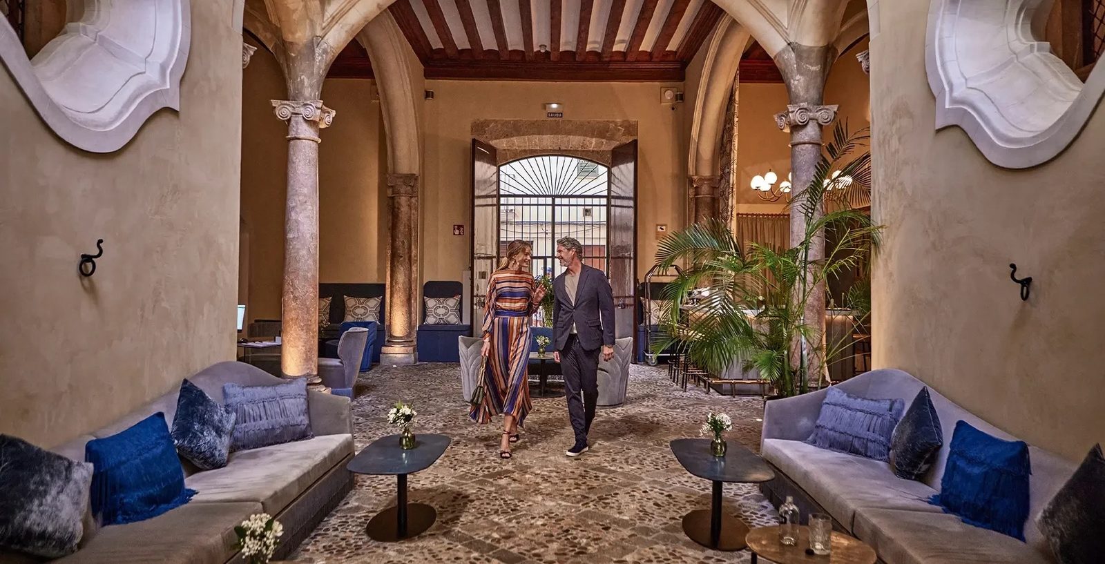 Stone courtyard with slender columns, arches and lounge seating inside the palace