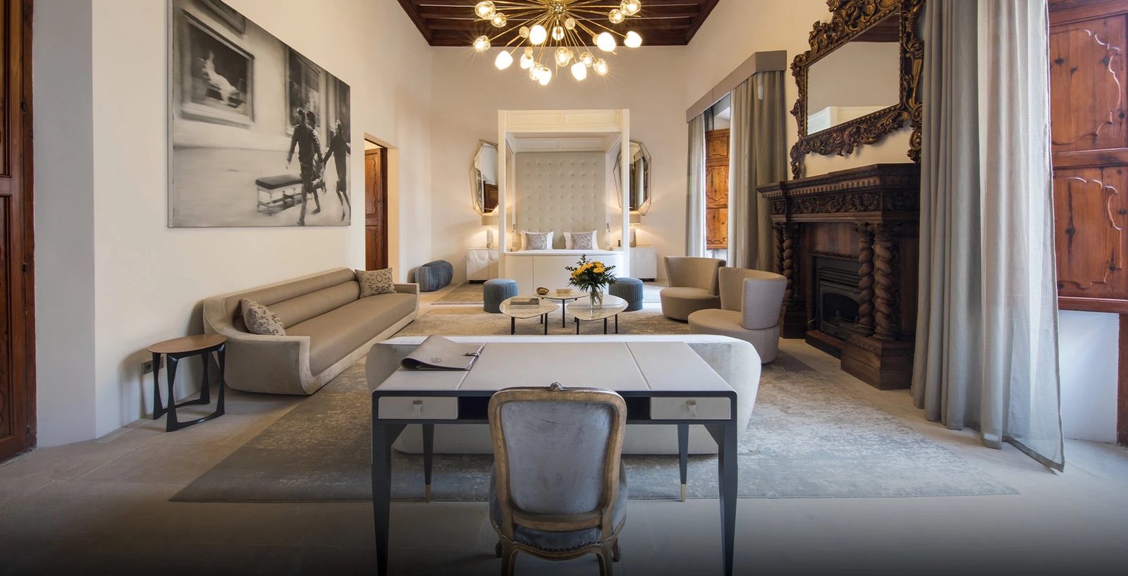 High-ceilinged Signature Suite with a lounge area, fireplace and bed behind