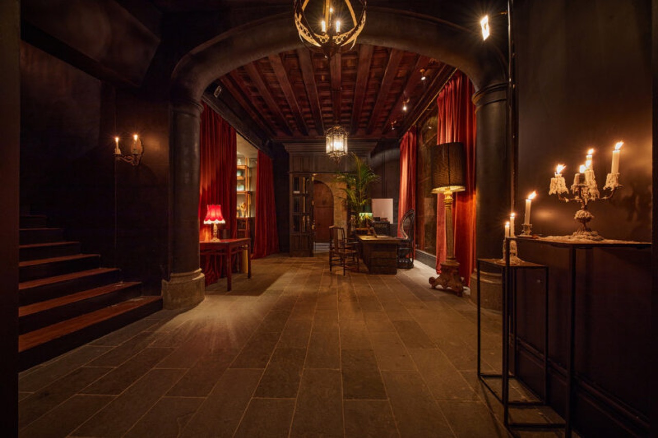 Candlelit stone corridor at Palma Riad with red velvet curtains and a vaulted archway