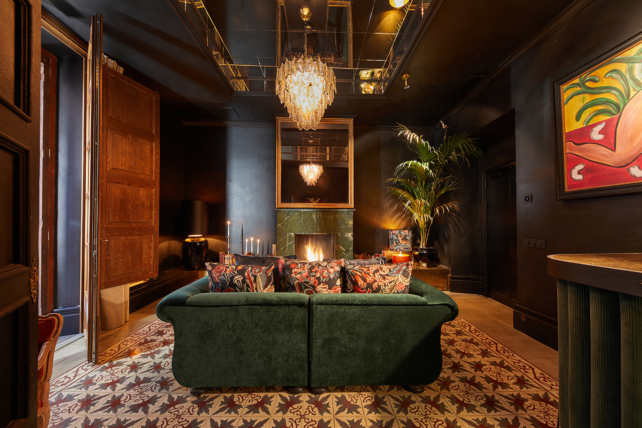Lounge at Palma Riad with a green velvet sofa facing a marble fireplace and mirrored ceiling