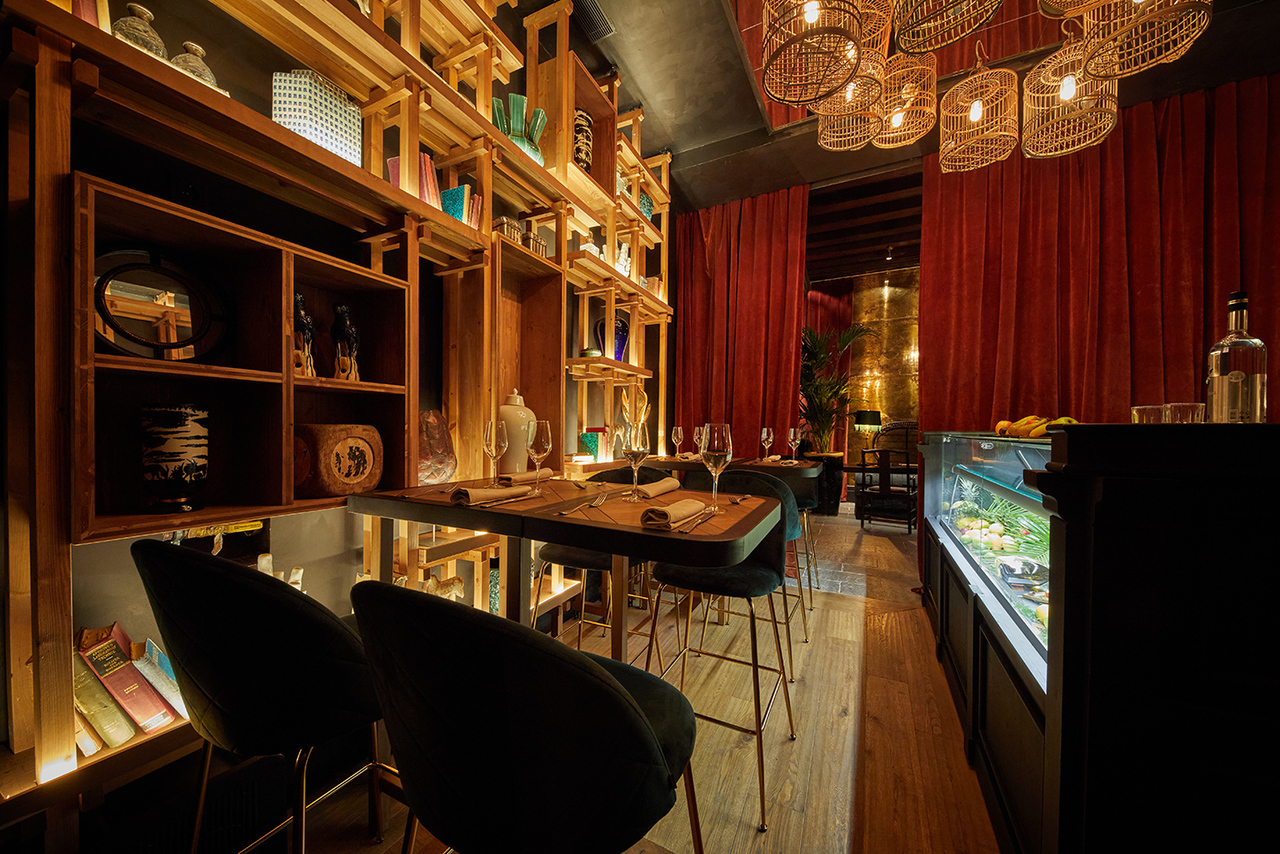 Dining area at Palma Riad with wine glasses set on wood tables beneath rattan pendant lights