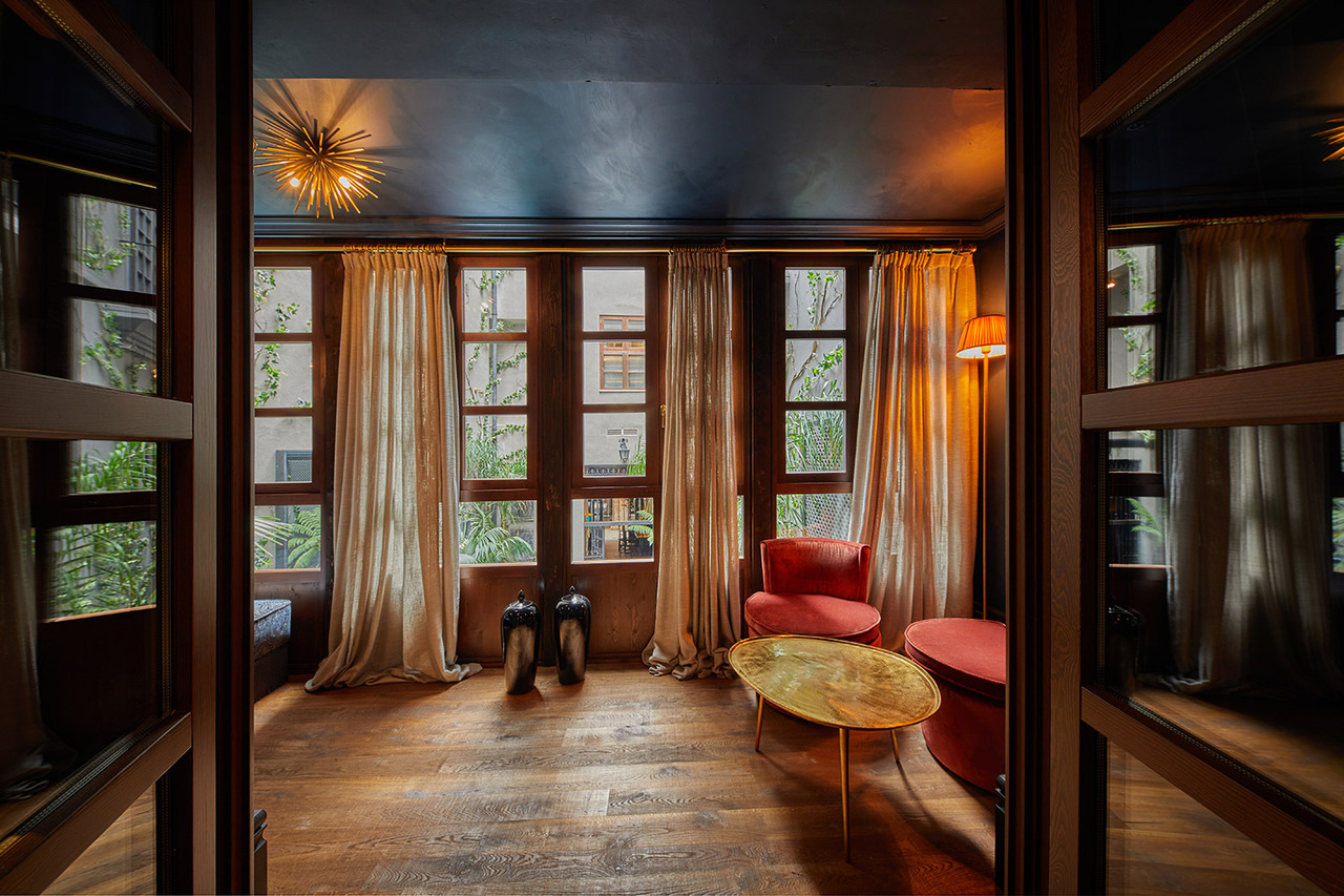 Sitting room at Palma Riad with tall curtained windows looking onto the courtyard