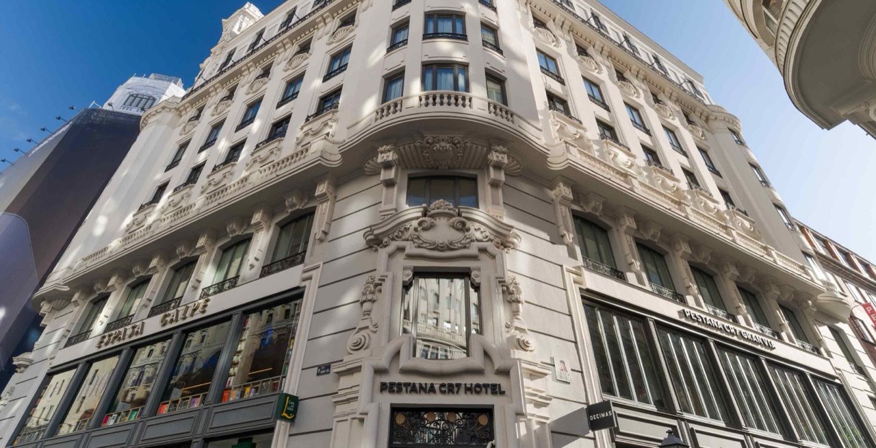 Ornate early-20th-century corner building on Gran Vía with carved stone facade and balconies, 'Pestana CR7 Hotel' signage above the entrance.