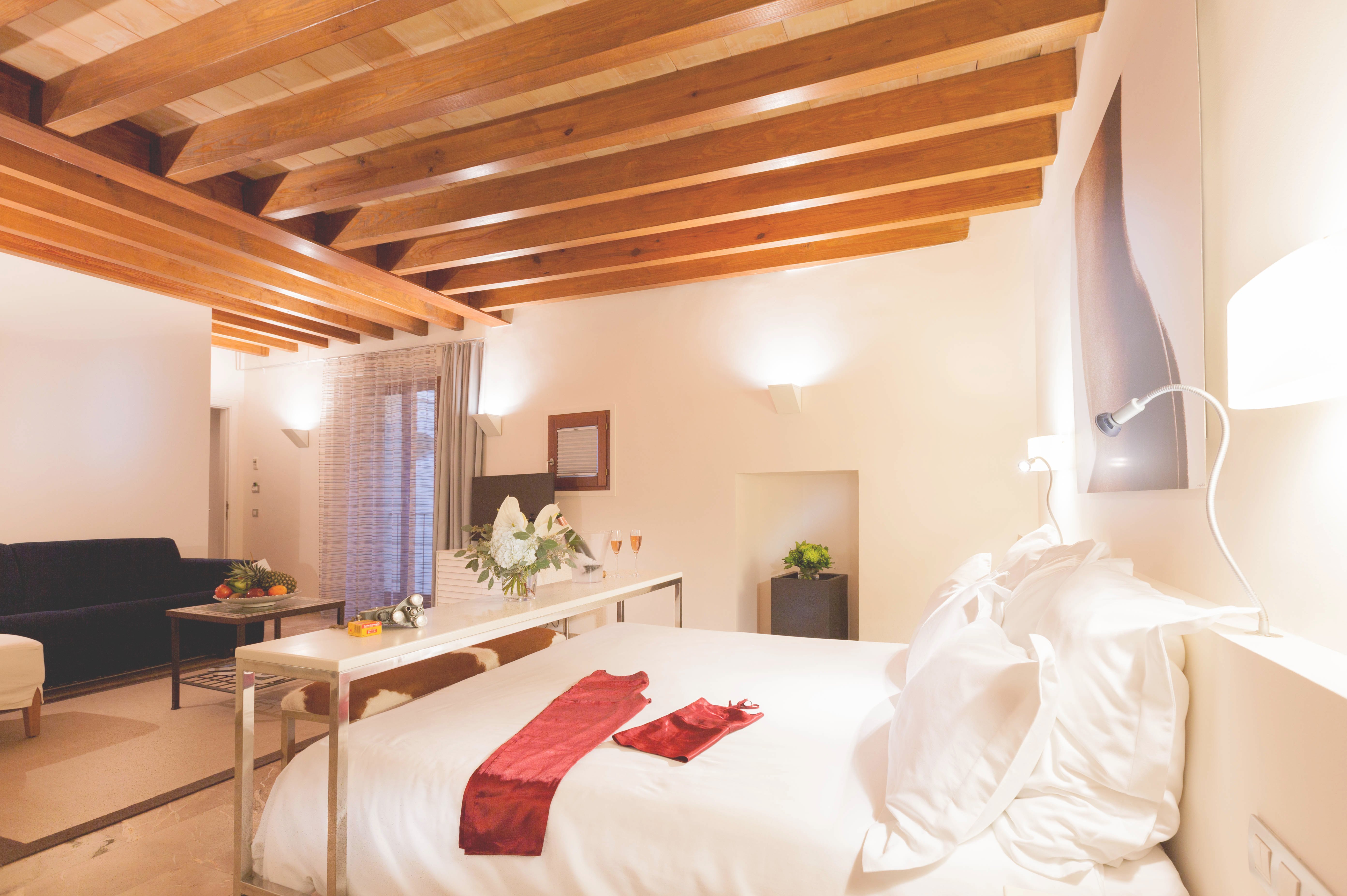 Junior Suite with exposed timber beam ceiling, a sitting area and a bed dressed with turndown accents