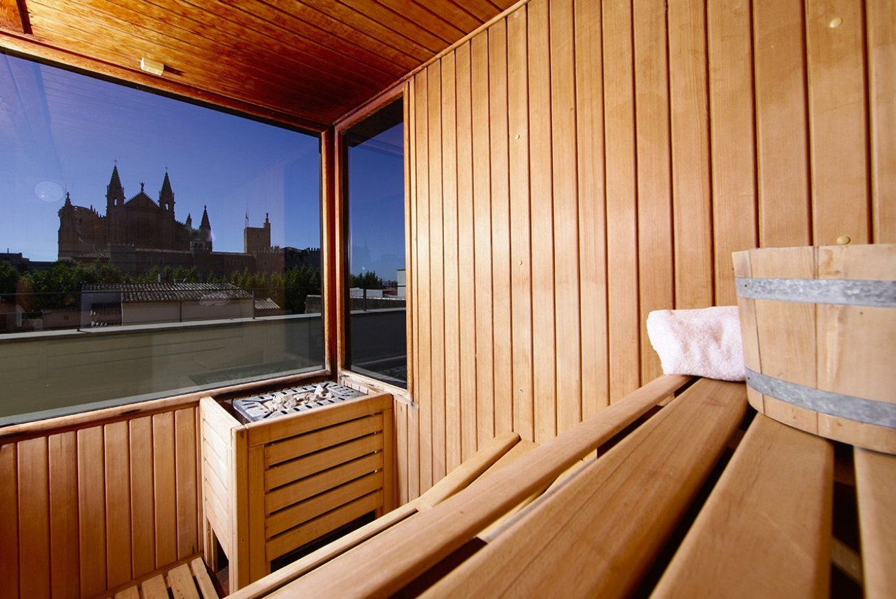 Wood-panelled sauna with a view through the window to Palma Cathedral at dusk