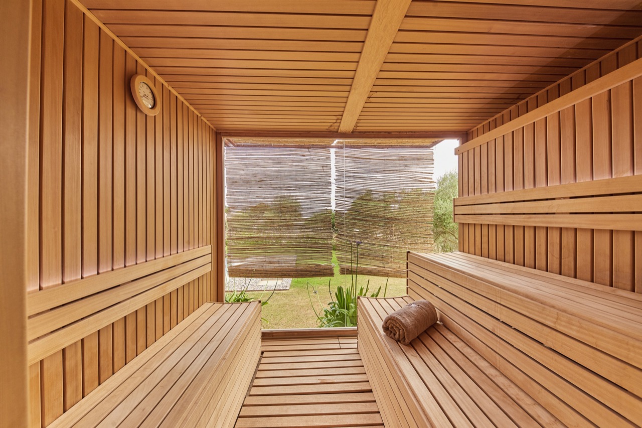 Wooden sauna with a garden view through a glass wall