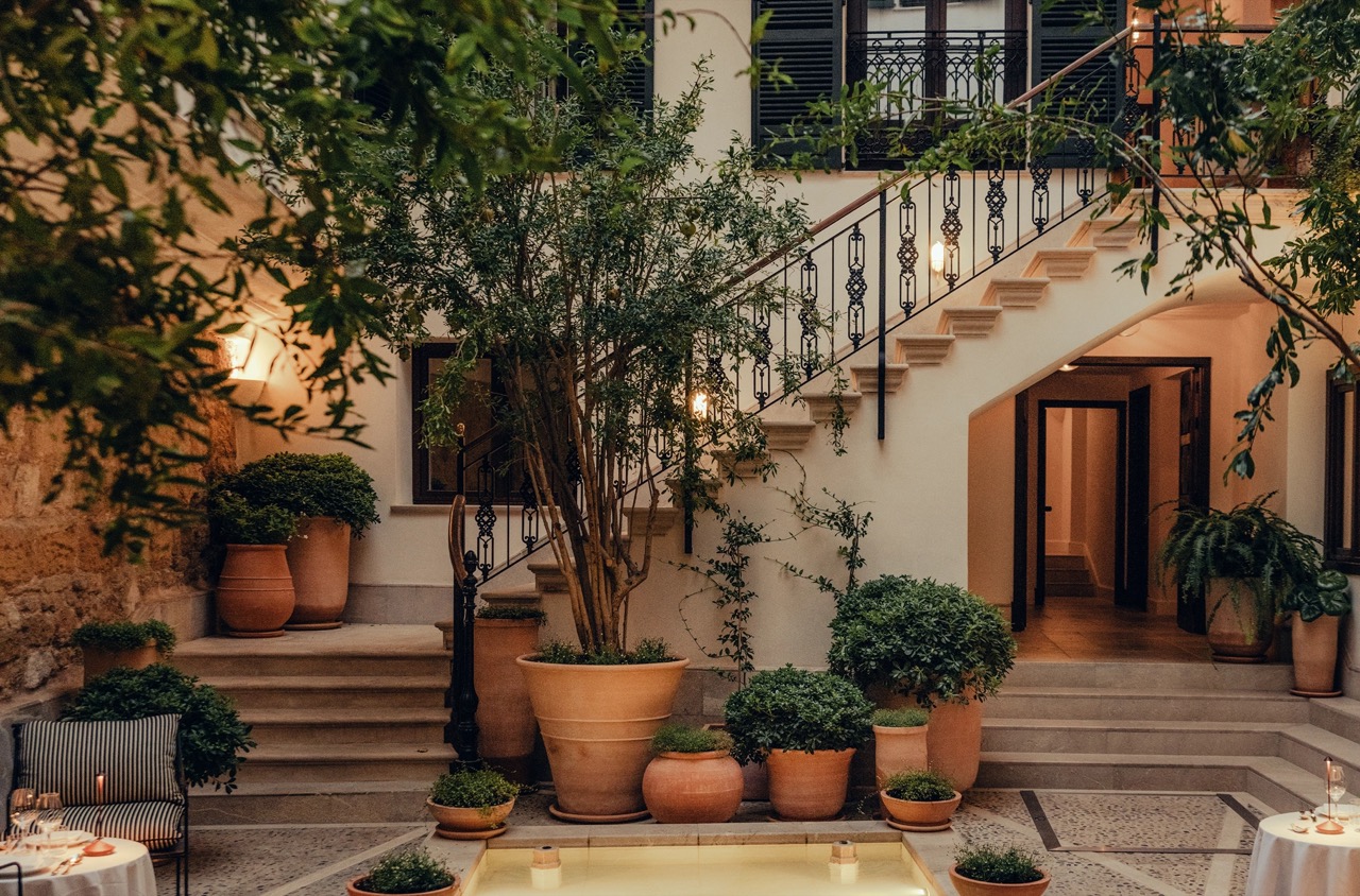 Historic stone courtyard with a staircase, potted plants and a small reflecting pool