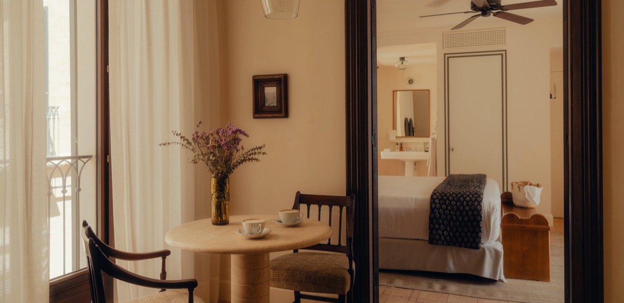 Suite sitting area with a round table opening onto a wrought iron balcony