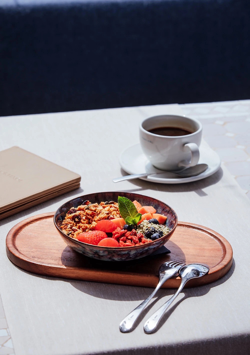 Breakfast granola bowl with fresh fruit and coffee served on the restaurant terrace table