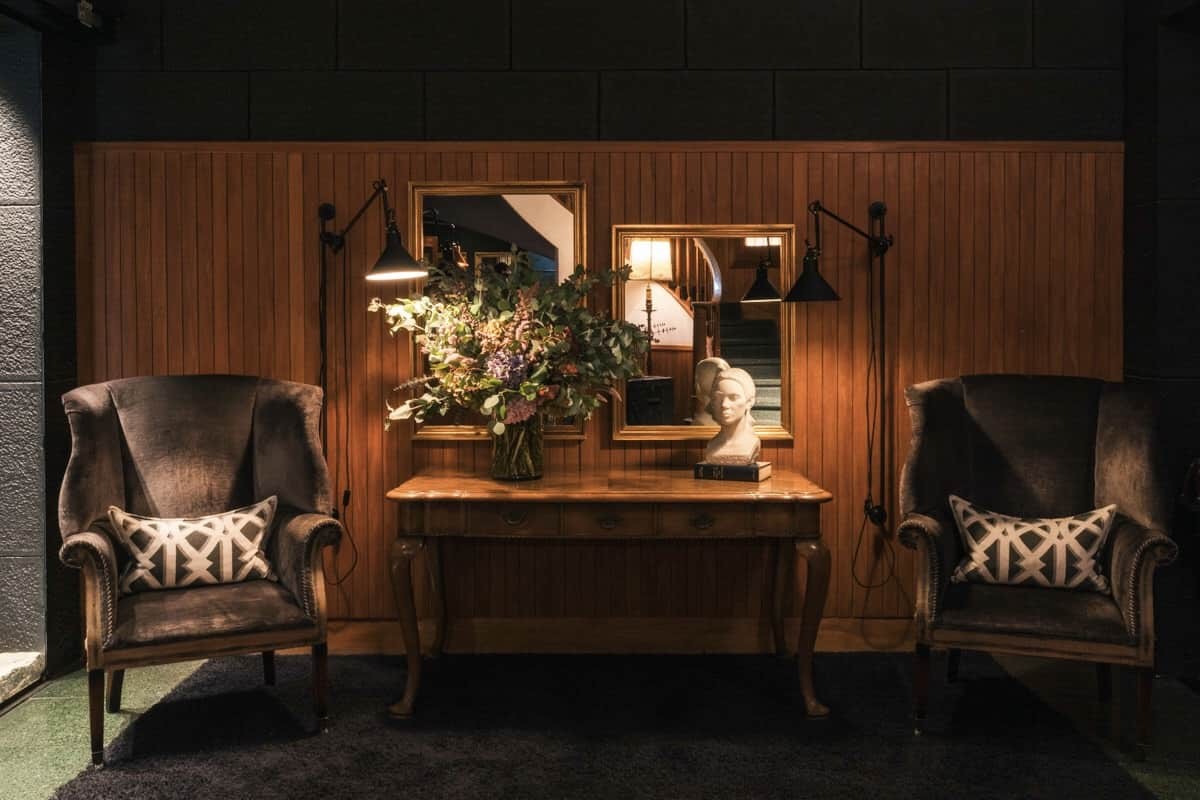 Reception seating with wingback chairs, a console table and mirrors