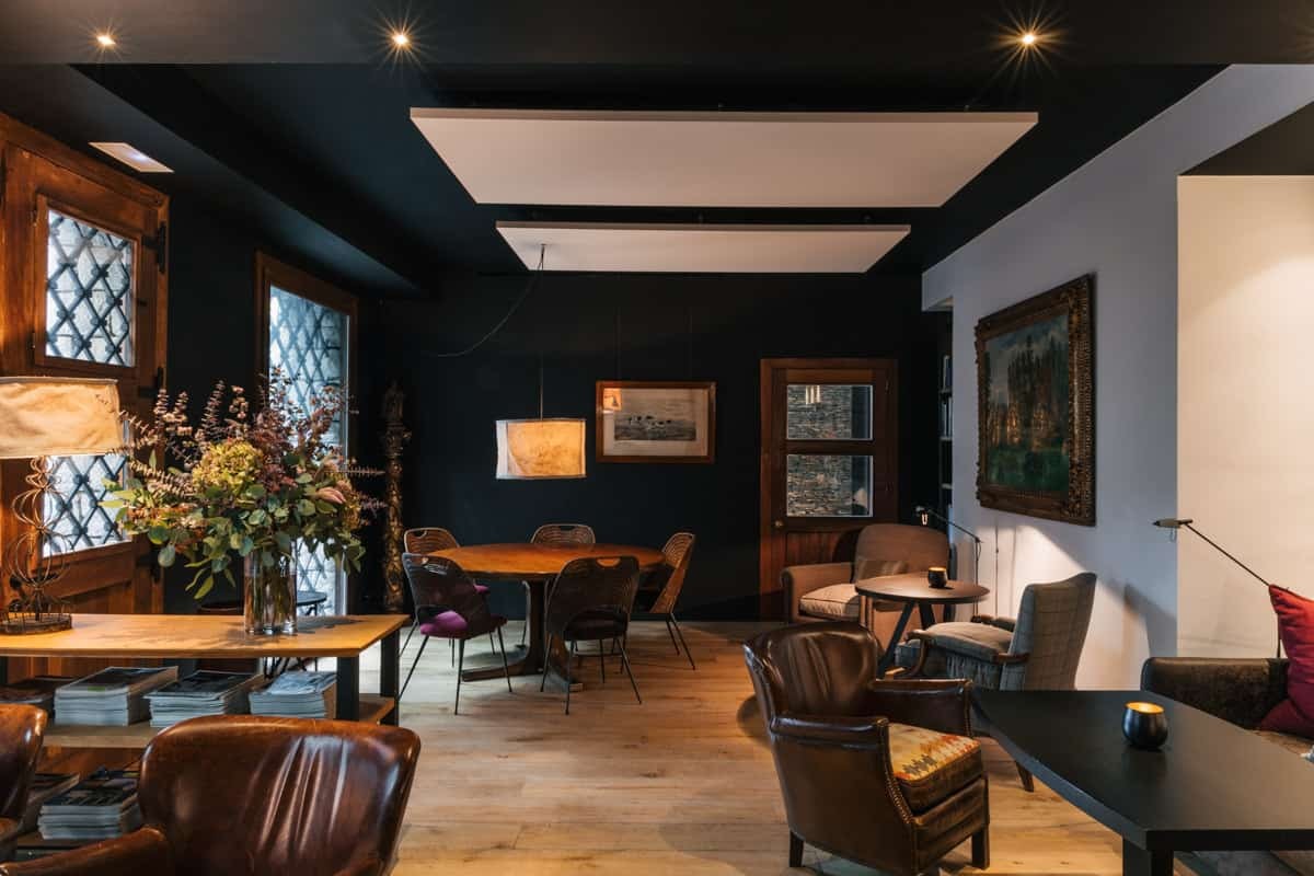 Dark-walled lounge with leather armchairs, a dining table and framed art