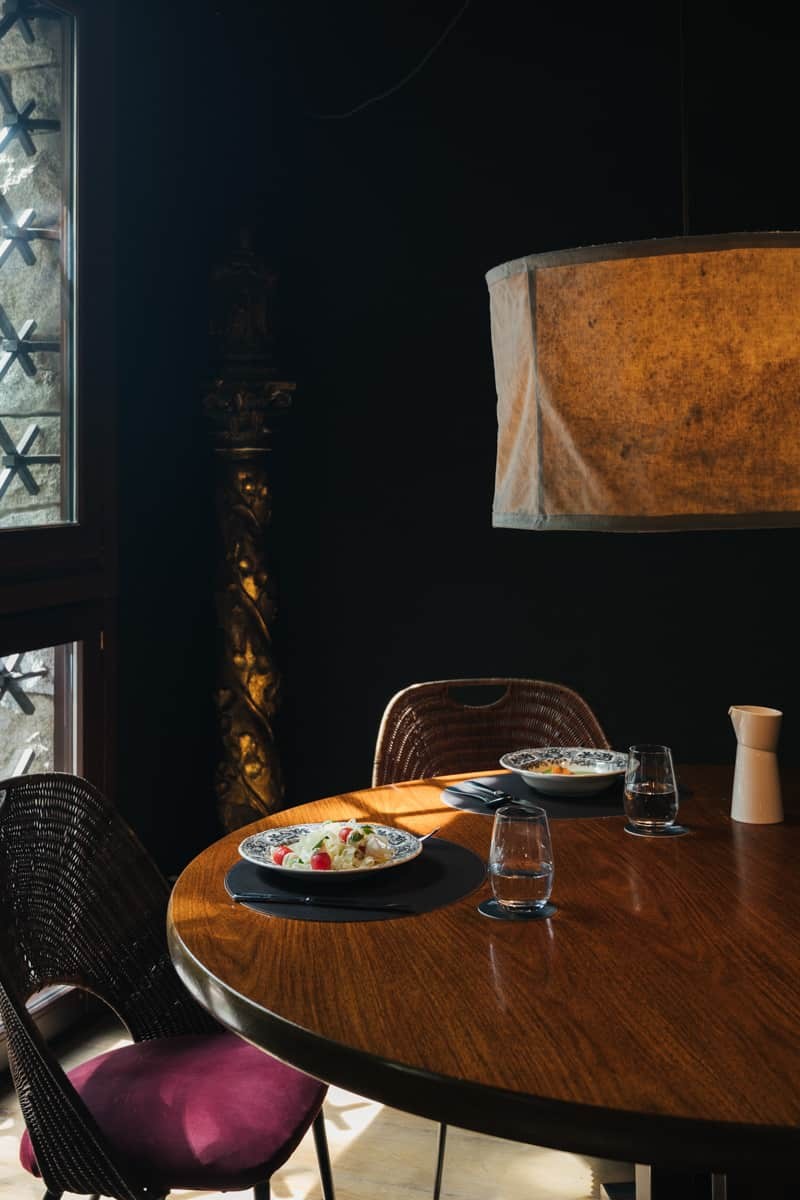 Restaurant table set with plated dishes under a fabric pendant lamp