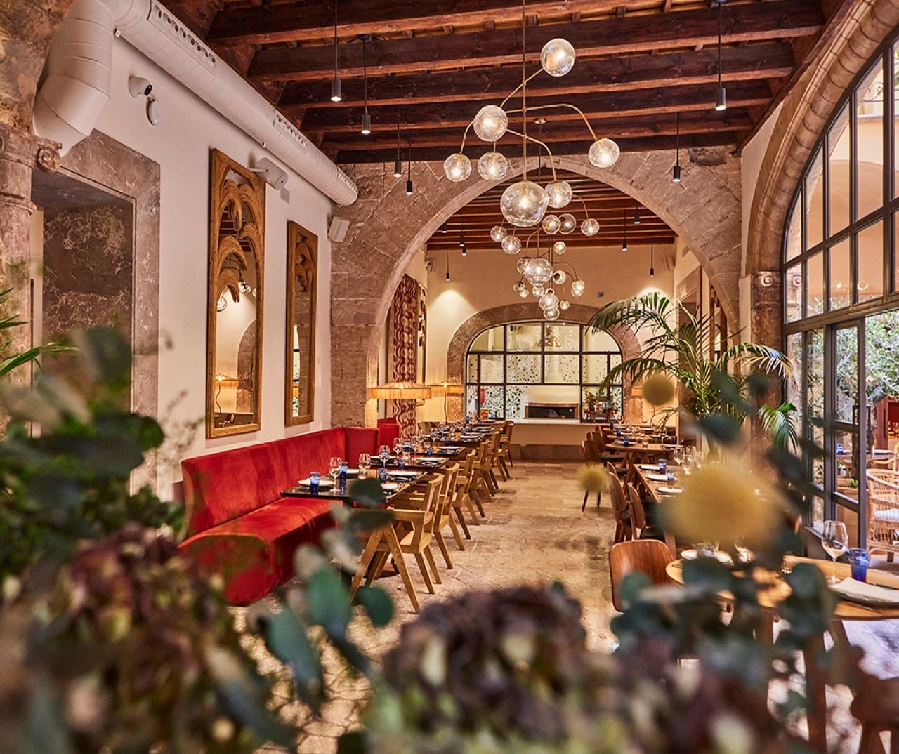 Restaurant dining room with stone arches, exposed wood beams and a red banquette