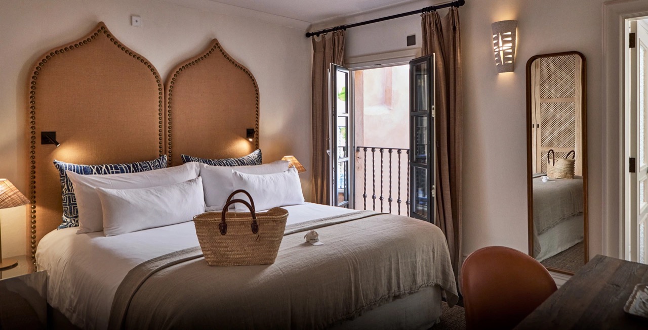 Room with a arched headboard and doors opening onto a wrought iron balcony