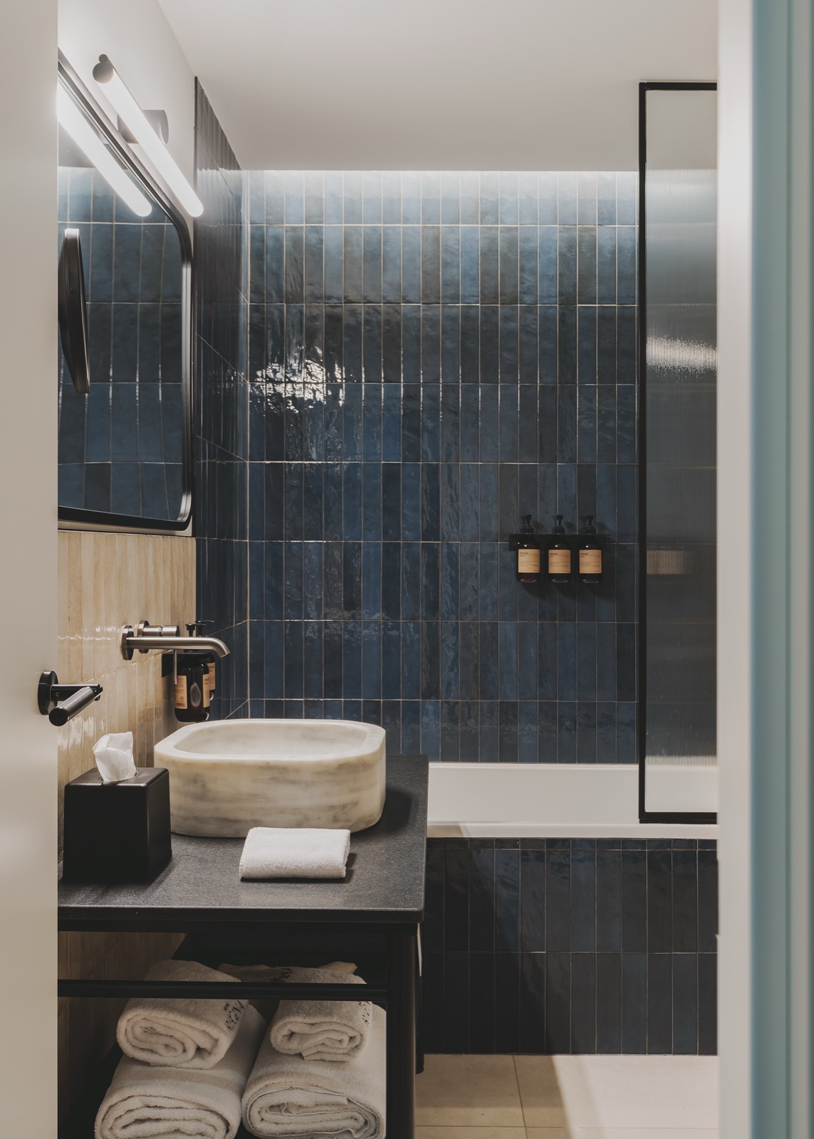 Bathroom with blue zellige tile, a stone vessel sink and a freestanding tub