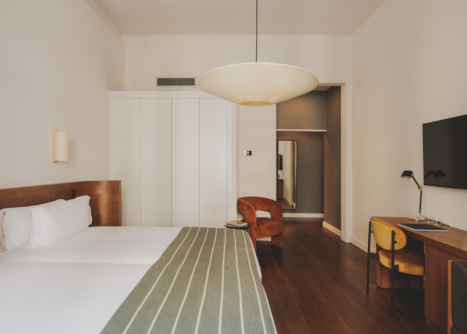 Guest room with a wood headboard, a desk and a mustard armchair