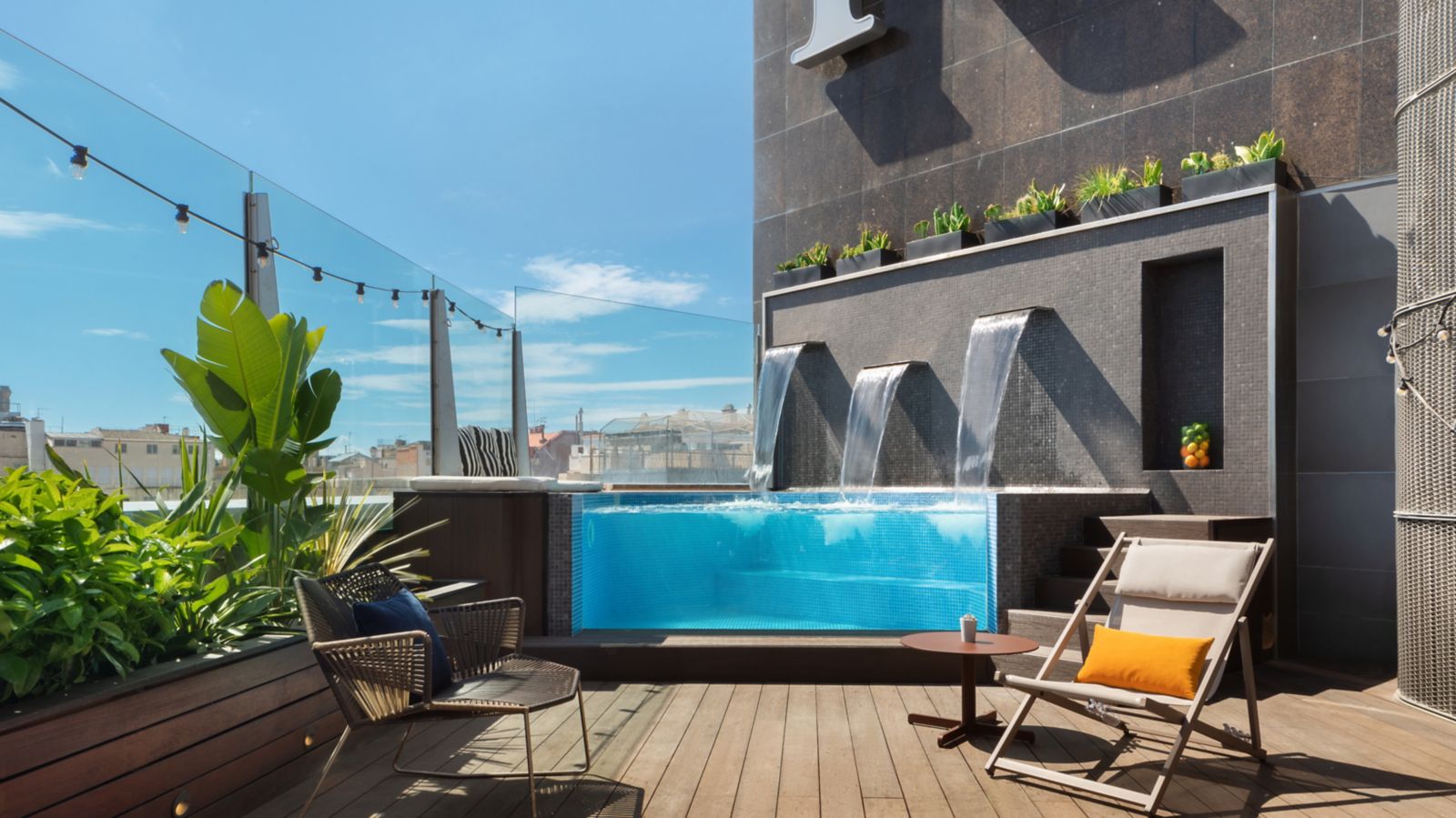 Rooftop plunge pool with a waterfall wall and deck chairs