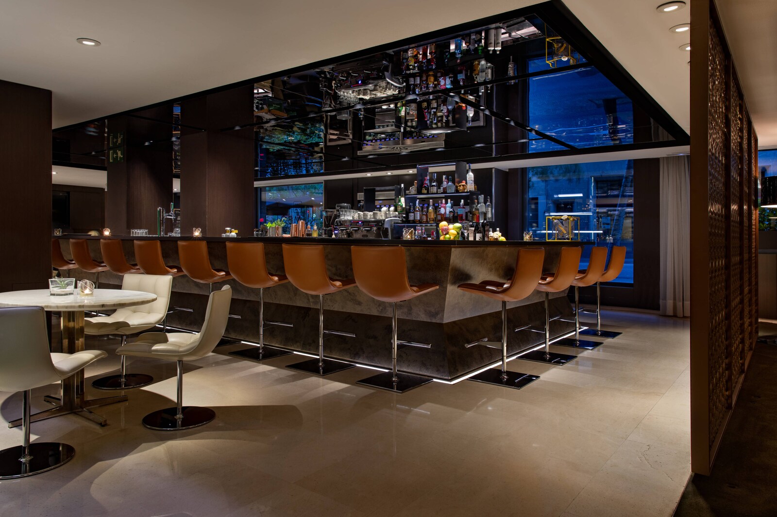 Rumbo Bar with a backlit bottle display and leather stools