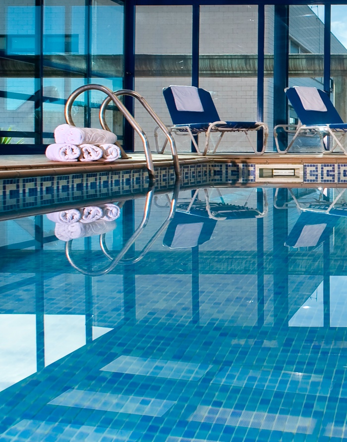 Indoor pool with a tiled surround and poolside loungers