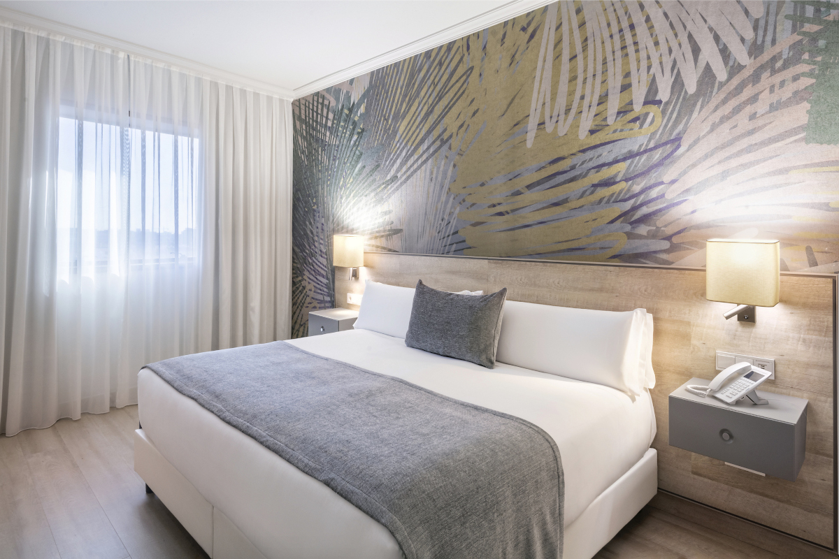 Room with a palm-leaf wallpaper headboard and a king bed