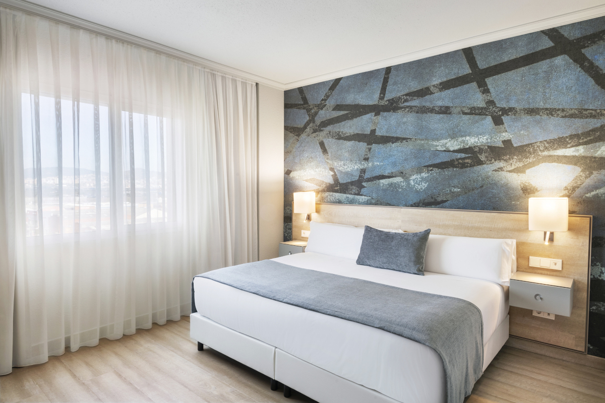 Room with a blue geometric wallpaper headboard and a king bed