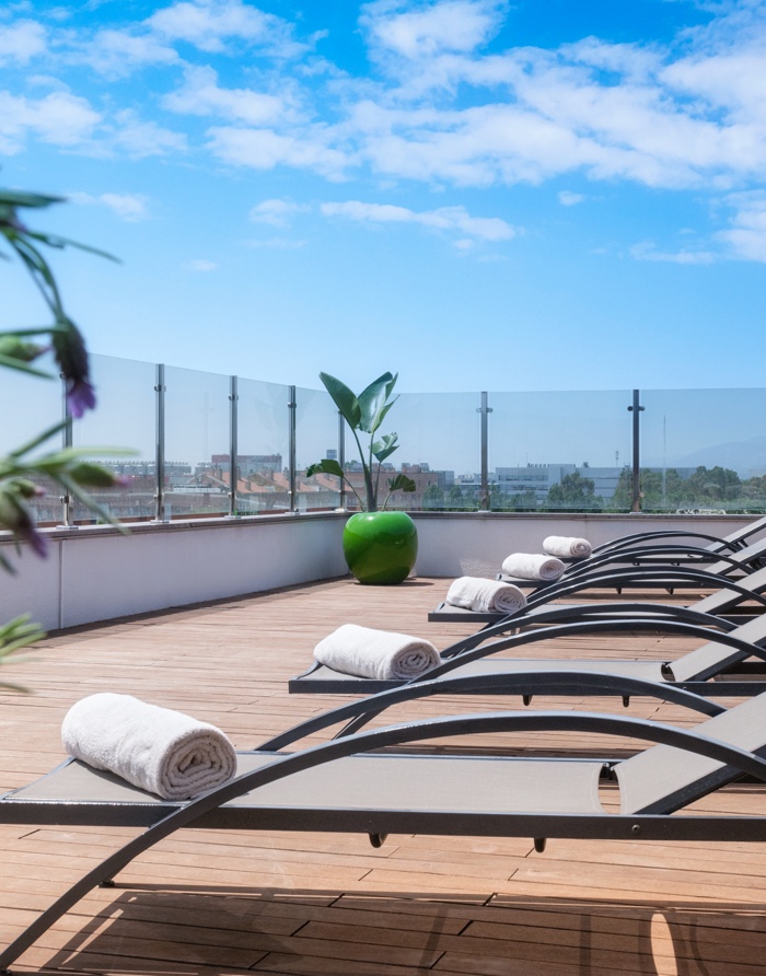 Rooftop terrace with sun loungers and a city skyline view