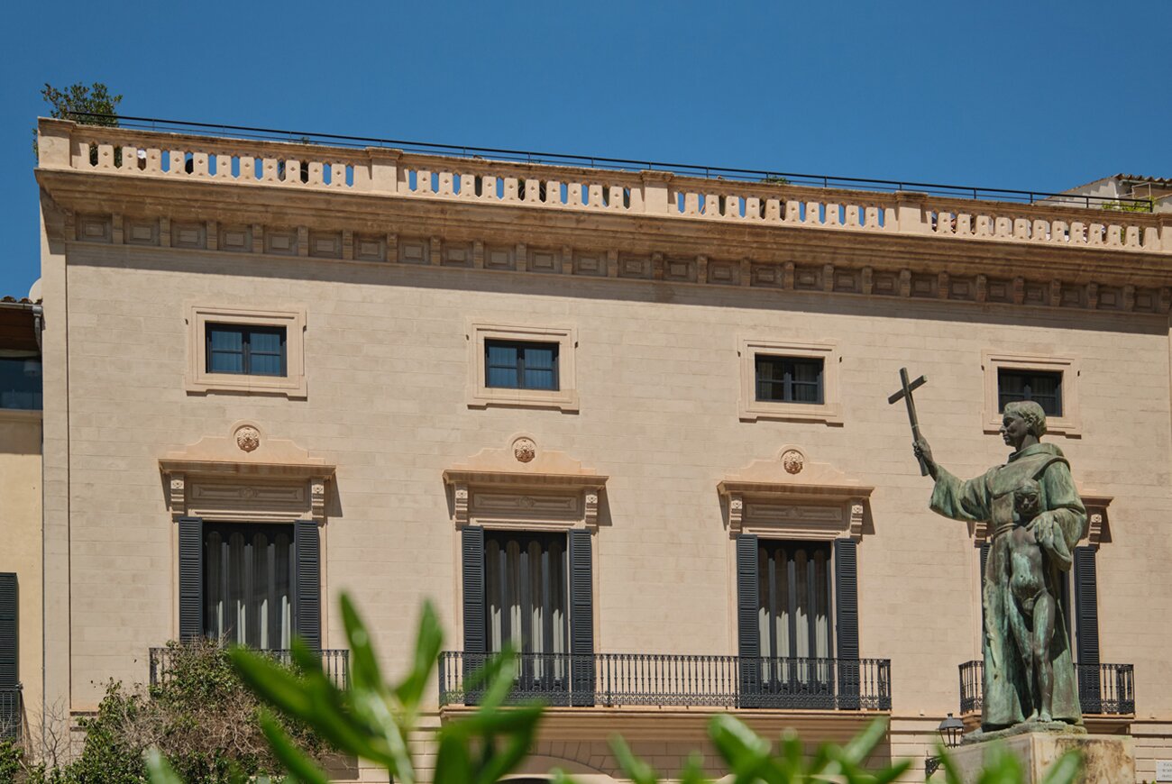 Sand colored stone facade of the hotel with a statue in front