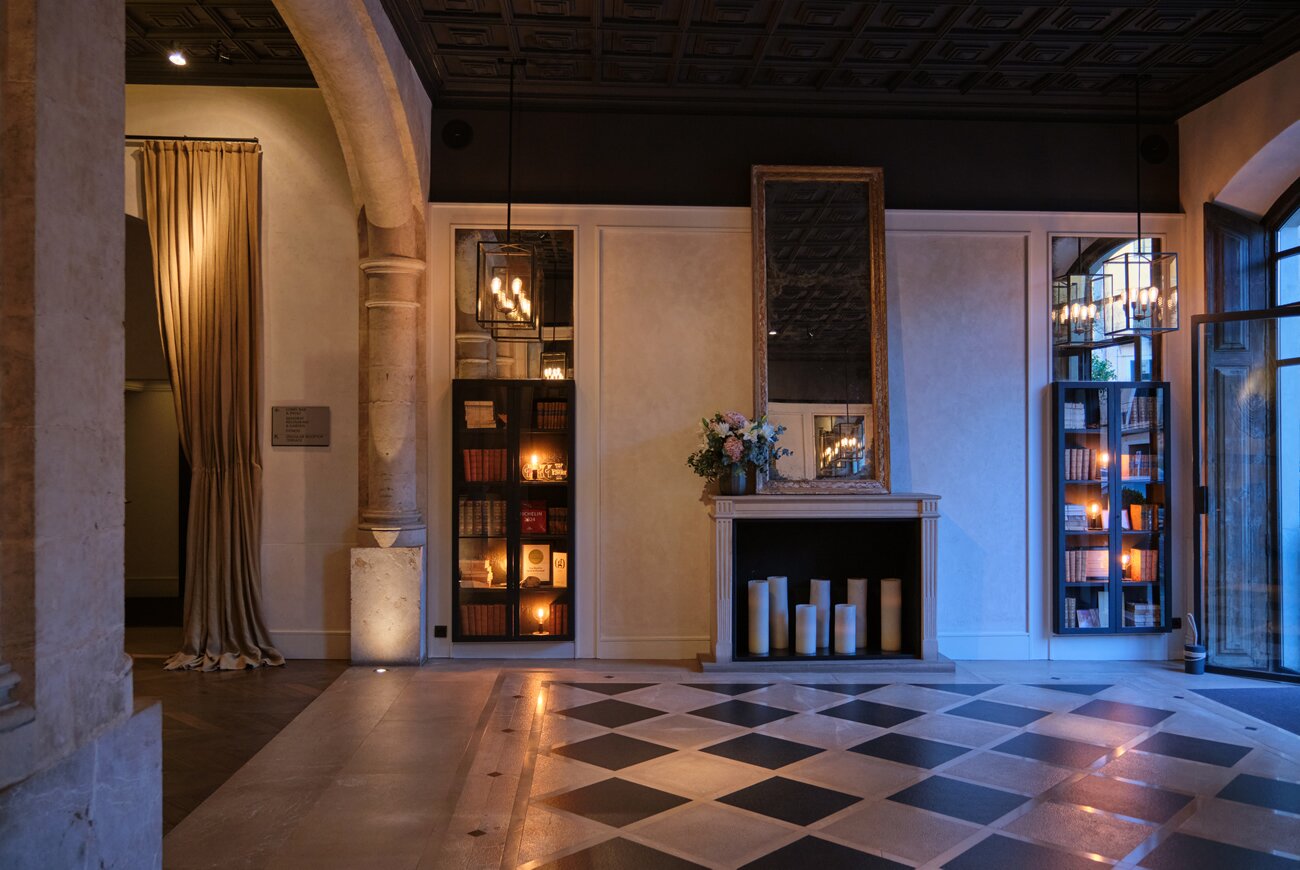 Lobby with checkerboard floor, fireplace and glass display cabinets of books