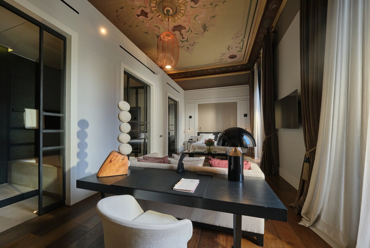 Suite with painted ceiling, sitting area and glass walled bathroom