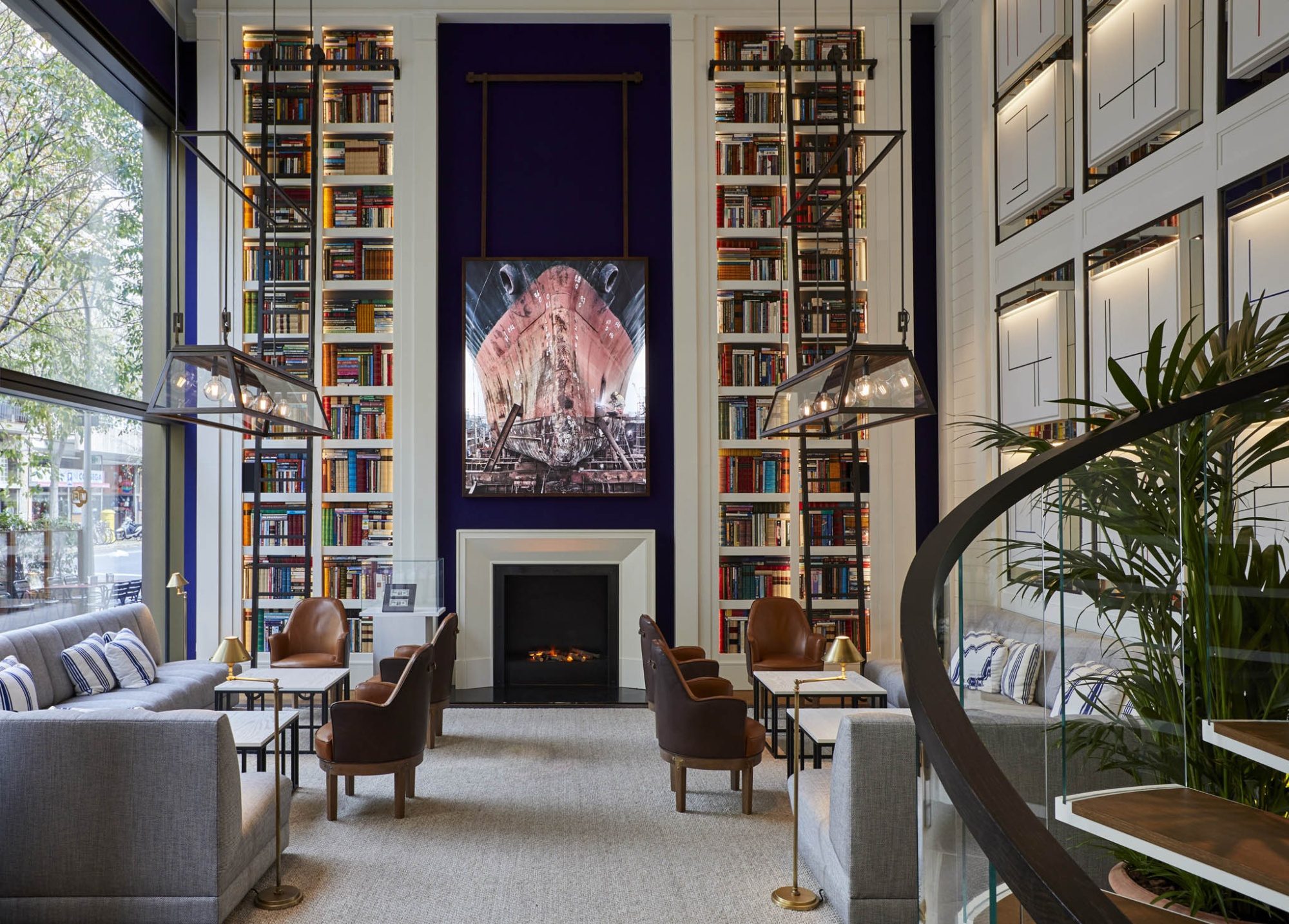 Lounge at Seventy Barcelona with floor-to-ceiling bookshelves flanking a fireplace and a spiral staircase to one side