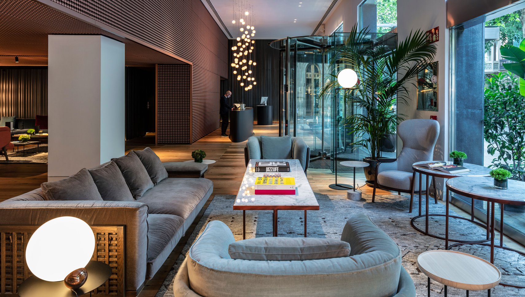 Hotel lobby with wood-slat walls, a sculptural chandelier and lounge seating