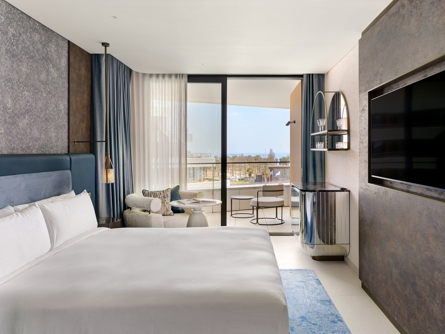 Captivate King Terrace room at SLS Barcelona with a white bed, blue-grey curtains and glass doors to a terrace