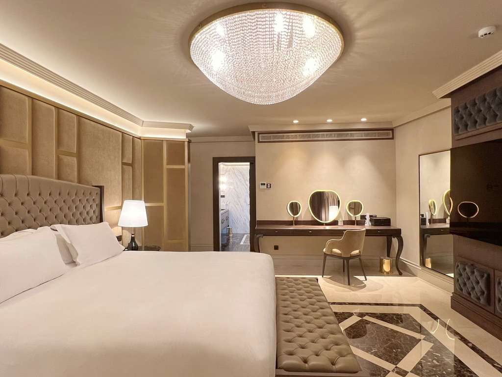 Presidential suite bedroom with a tufted headboard and a chandelier