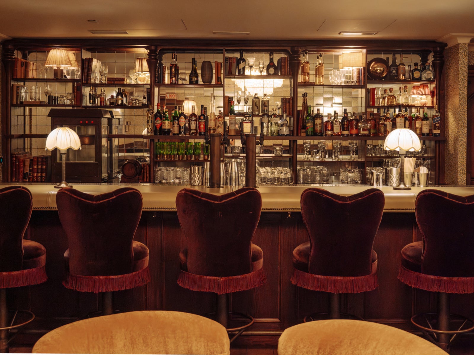 Bar with mirrored back-bar shelving and velvet stools