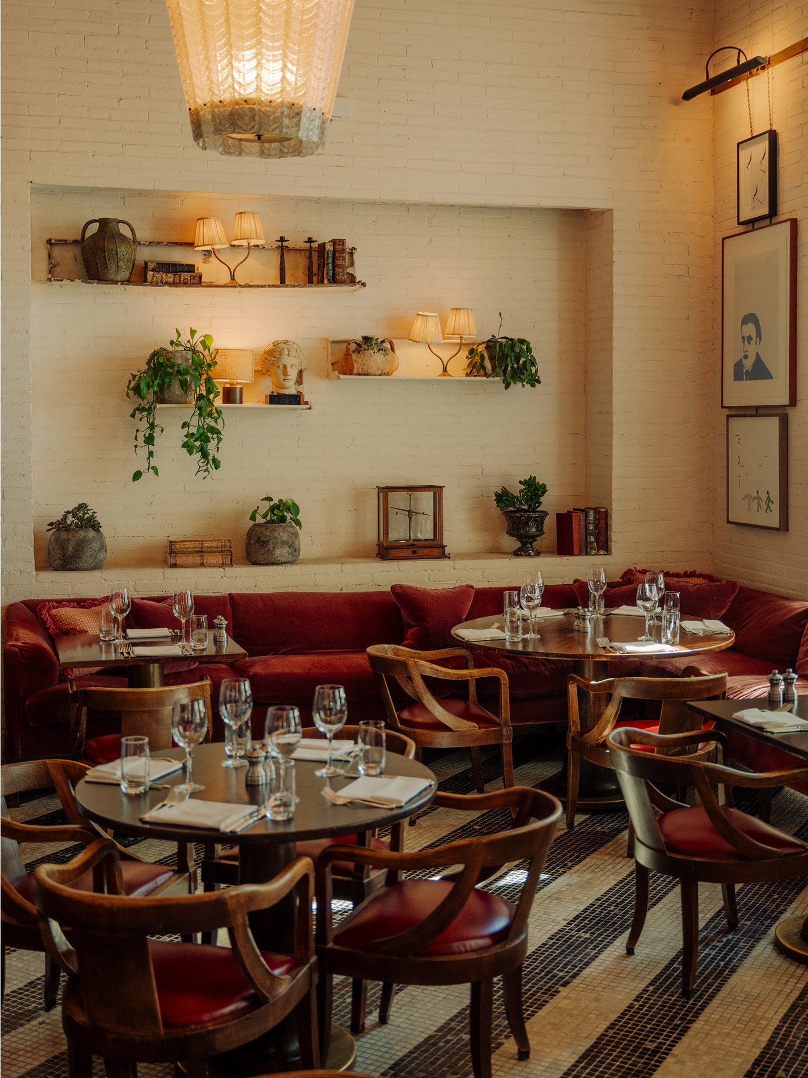 Restaurant with red velvet banquettes and curated wall shelving