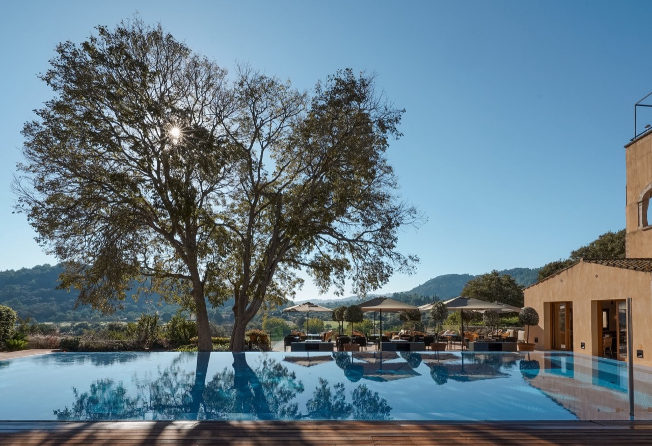 Infinity pool at Son Brull at sunrise, with the monastery building and terrace loungers alongside