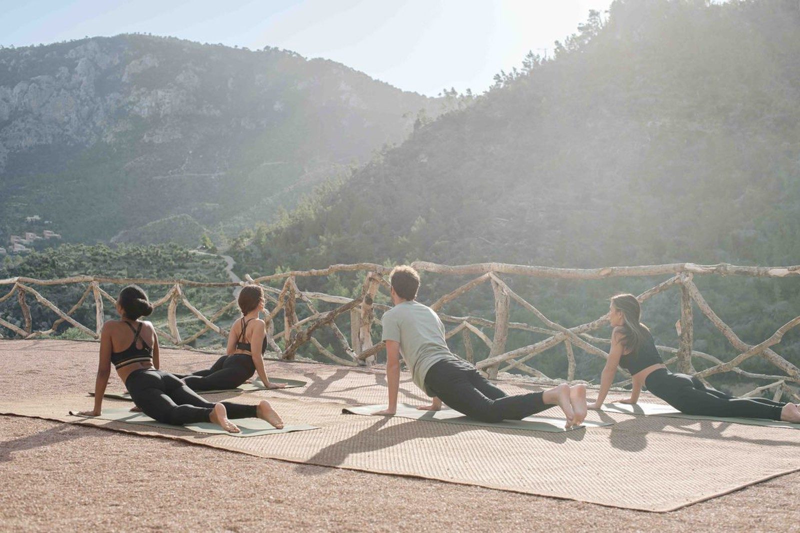 Outdoor yoga session on a wood-railed terrace at Son Bunyola with the Tramuntana mountains rising behind