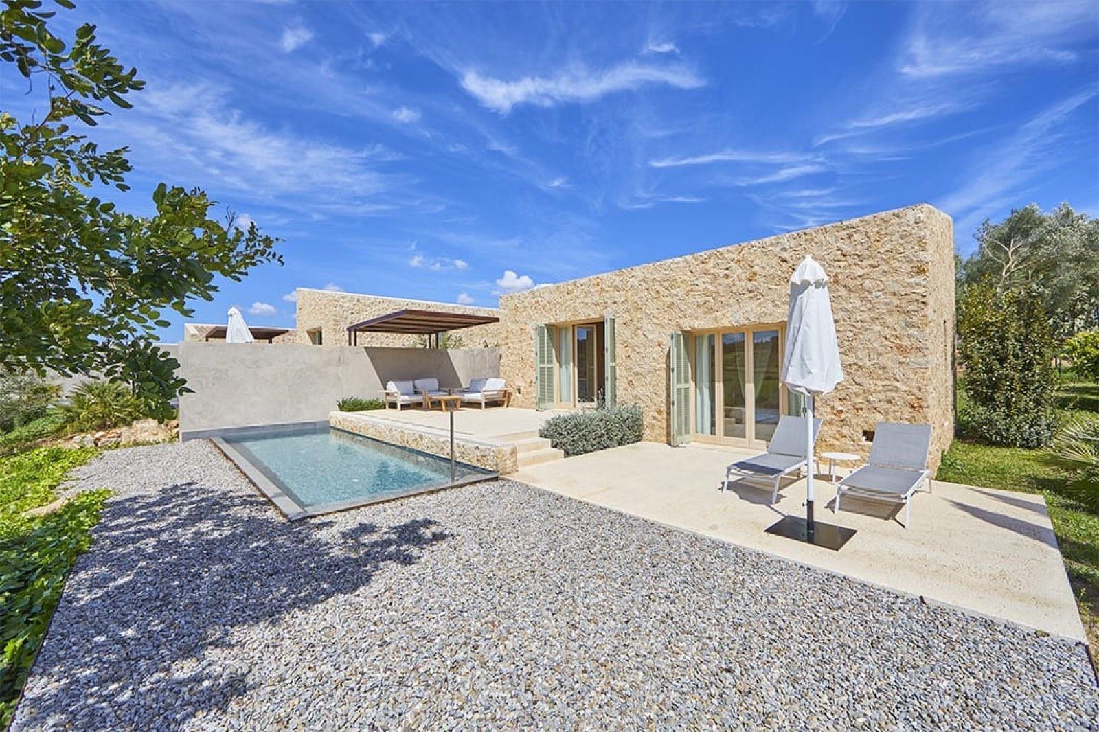 Gran Suite stone building with a private plunge pool, loungers and open green fields behind