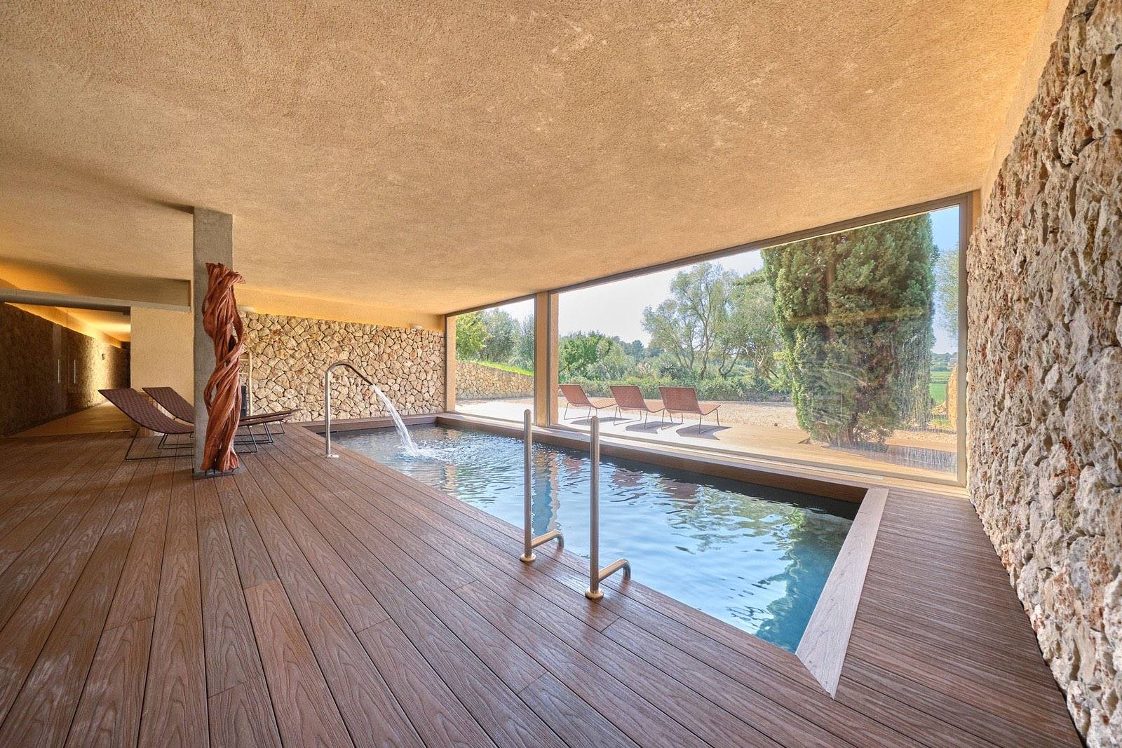 Indoor spa pool with a timber deck and a glass wall onto the garden
